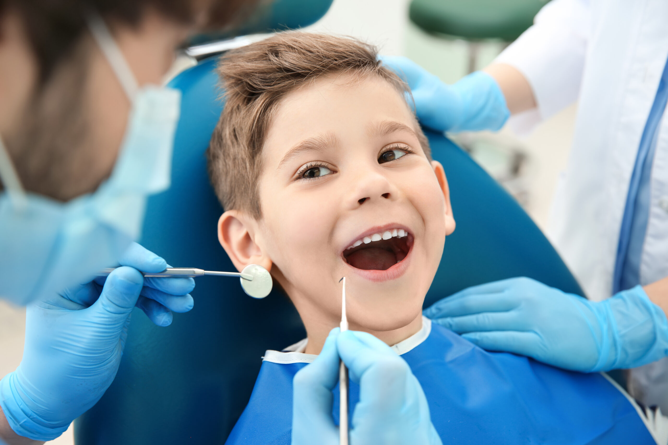 dentist,examining,little,boy's,teeth,in,clinic